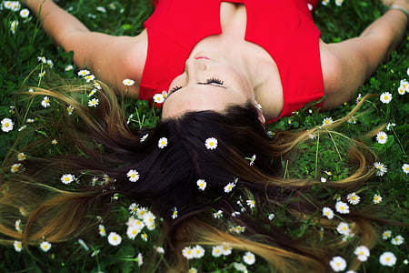 woman in red sleeveless top lying on green leaf plants