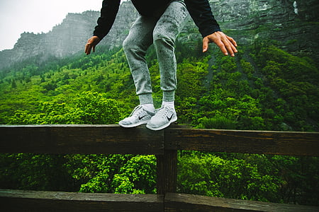 man standing on rail and mountain at distance