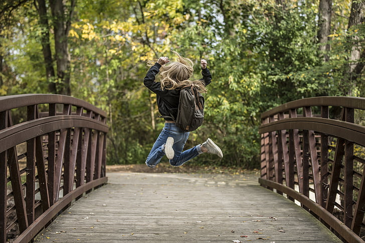 girl jump shot photo on brown wooden bridge
