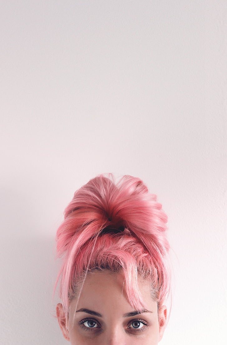 woman in pink hair beside white wall