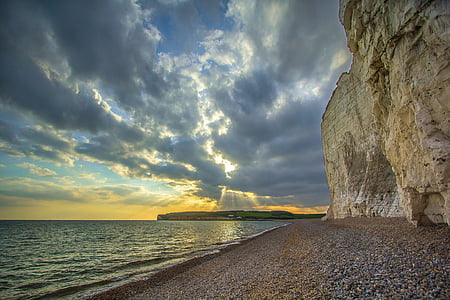 beige rock near seashore under grey clouds