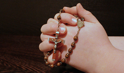 person holding brown rosary necklace