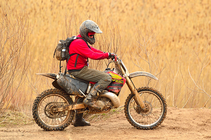 man in red jacket and grey pants riding on dirt bike