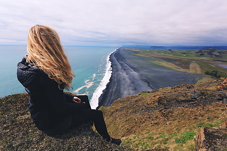 woman sitting on the rock facing on the seashore