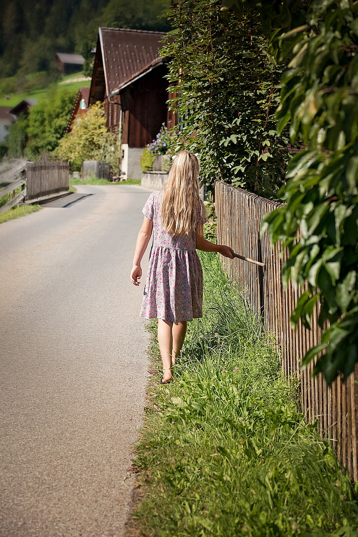 girl in dress standing on dress grass beside pathway