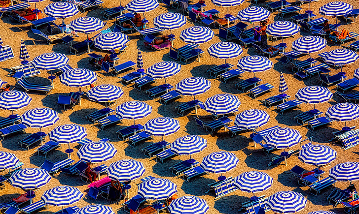 blue-and-white umbrella lot on white sand