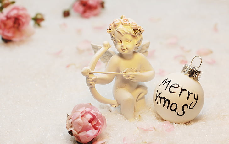 Cherub ceramic figurine beside of white Christmas ball