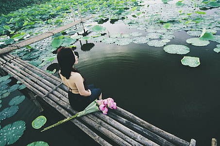 woman in black top sitting on brown bamboo dock