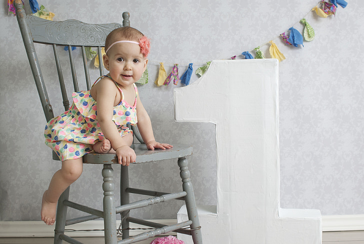 baby sitting on gray wooden chair