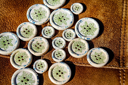 round white-and-green clothes button lot on brown textile