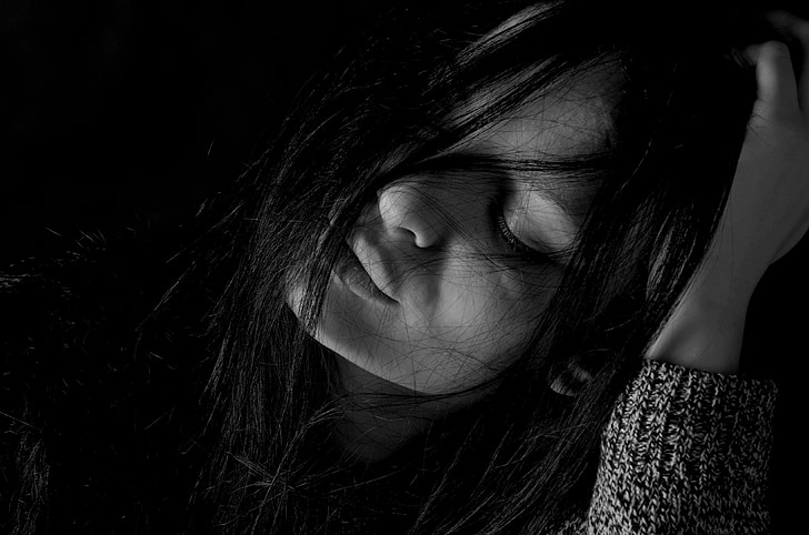 grayscale photography of woman holding her head