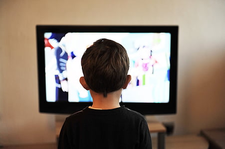 boy standing in front TV turned on