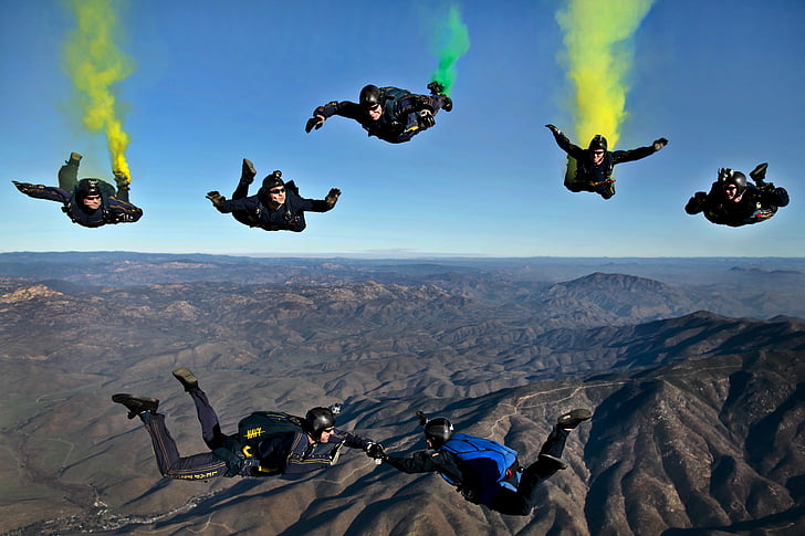 seven persons sky diving with parachutes under clear blue sky