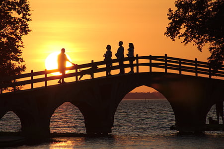 silhouette of persons on bridge during sunset