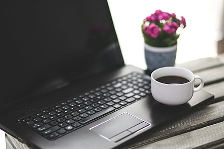 white teacup on black laptop computer