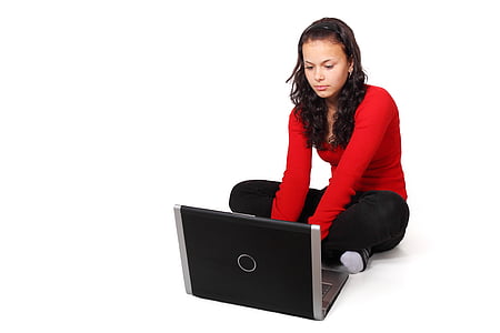 woman wearing red long-sleeve shirt and black pants on squat beside laptop