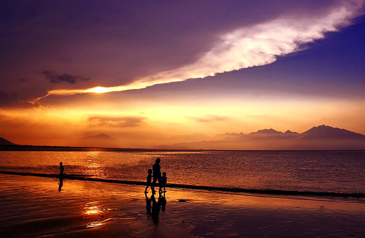 silhouette photo of four person near seashore