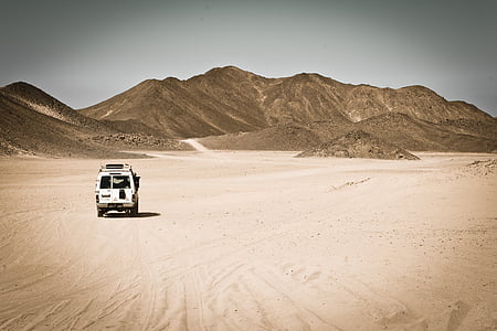 white SUV on the desert in a distance of a mountain