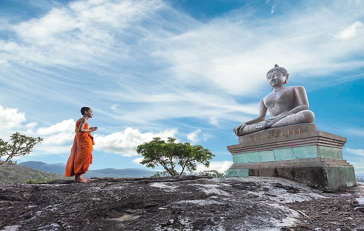 man praying in front of Gautama Buddha statue