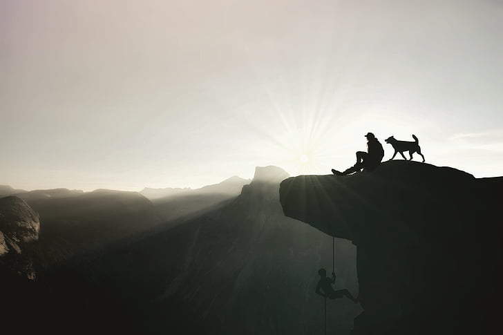 man and dog on top of mountain