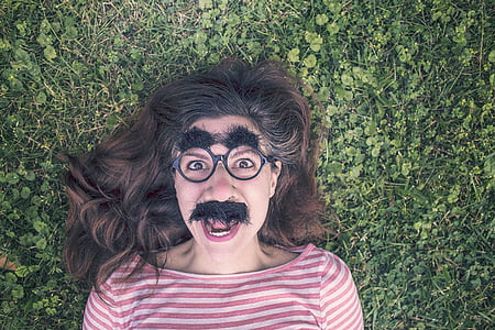 woman with fake mustache and eyebrow lying on green grass