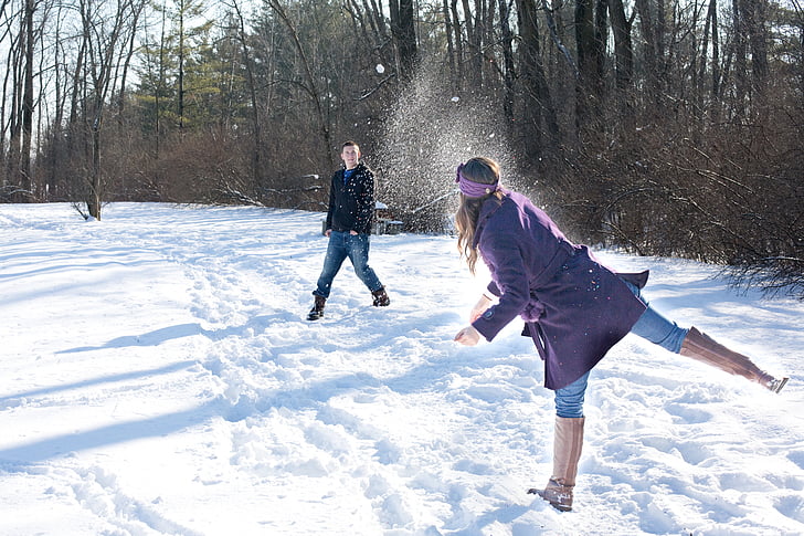 man and woman playing outside during winter