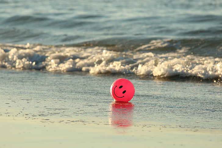 red smiley emoji ball on seashore