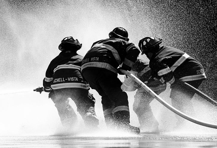 grayscale photo of firefighter holding fire hose