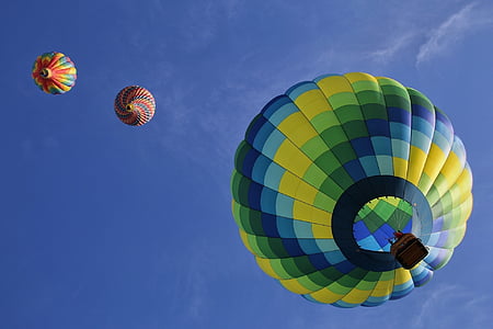 low angle view of three hot air balloons in mid air under blue sky