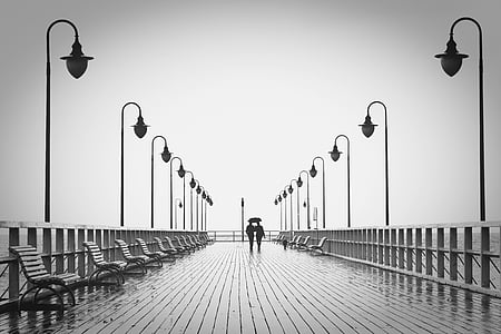 man and woman standing surrounded by light posts grayscale photograph