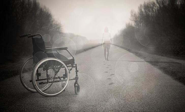 grayscale photo of wheelchair and faded woman