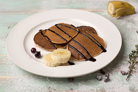 plate of pancakes with chocolate syrup and sliced banana