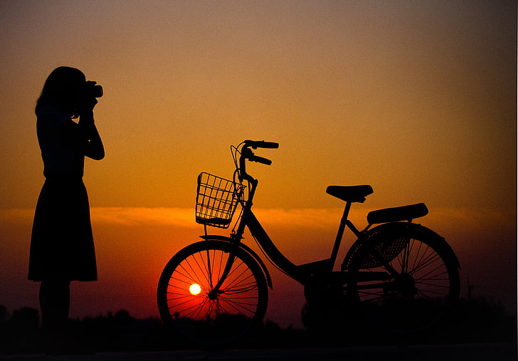 silhouette of woman and bicycle on