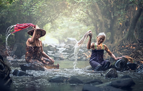 two sitting women on river washing clothes during daytime