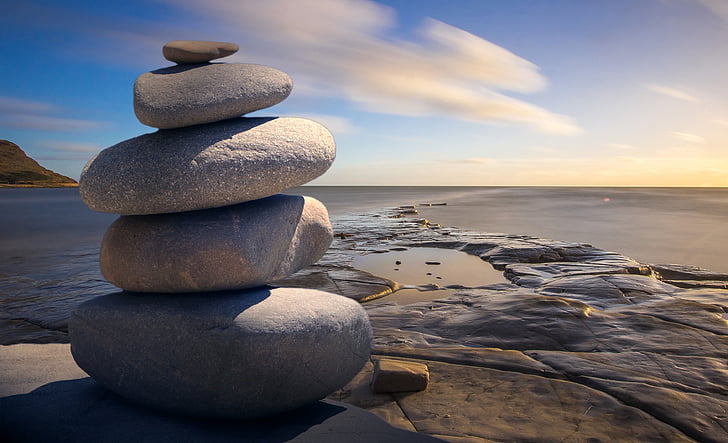 stack of grey rocks near brown surface under blue sky