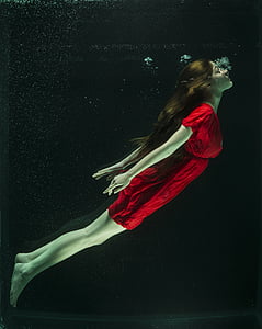 photo of woman in red dress under water
