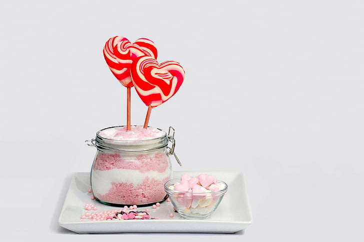 two heart-shaped red and white candies and clear glass jar
