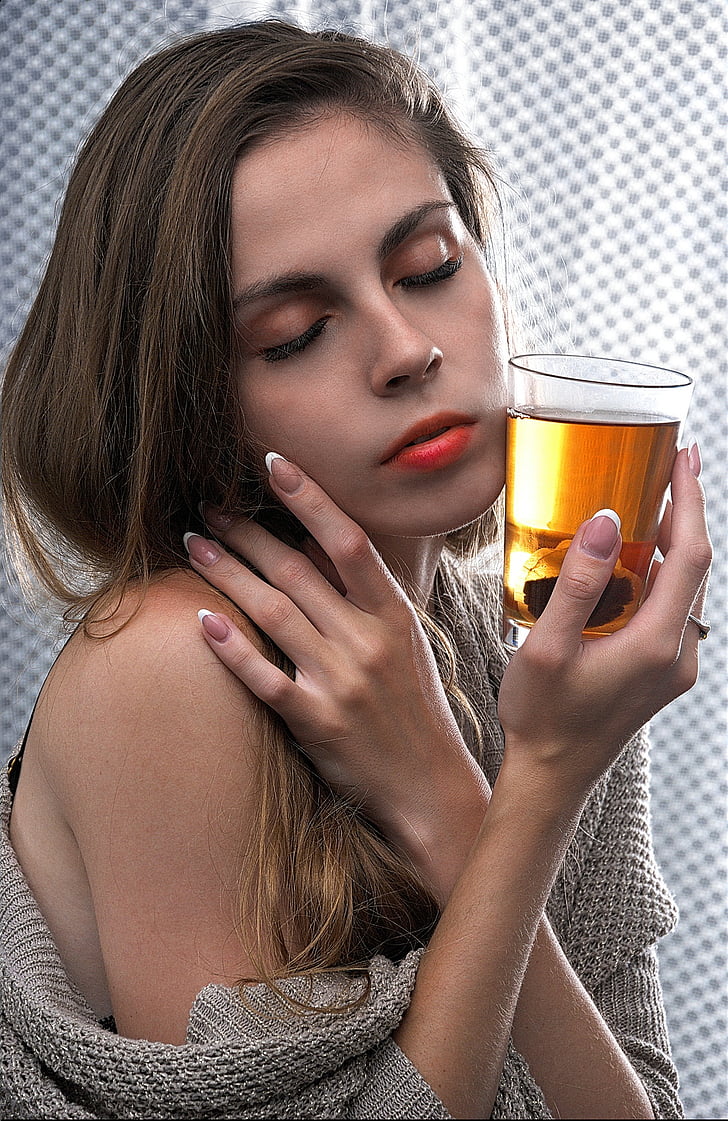 woman wearing gray sweater holding drinking glass