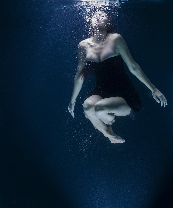 woman in black strapless dress under water