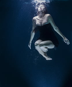 woman in black strapless dress under water