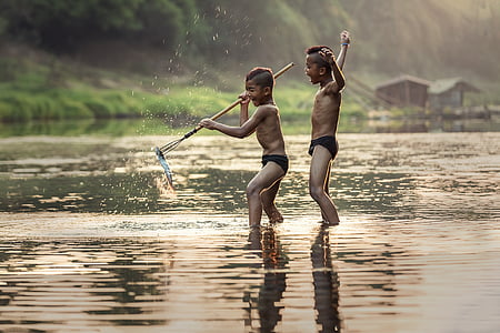 two boys standing on top of water during daytime