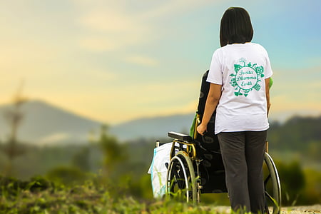 woman in white t-shirt holding black self-propelled wheelchair