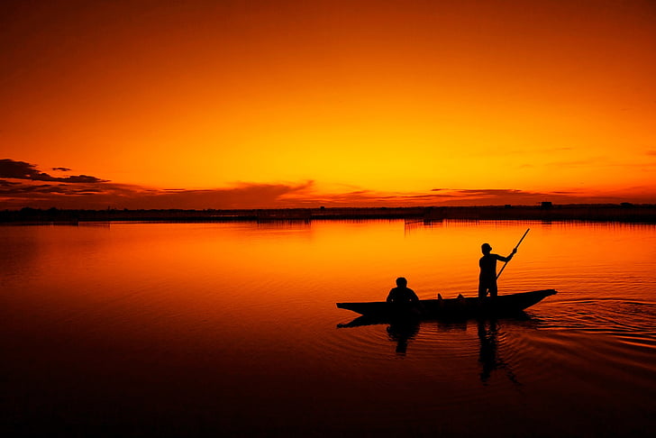 silhouette of two men on canoe during sunset