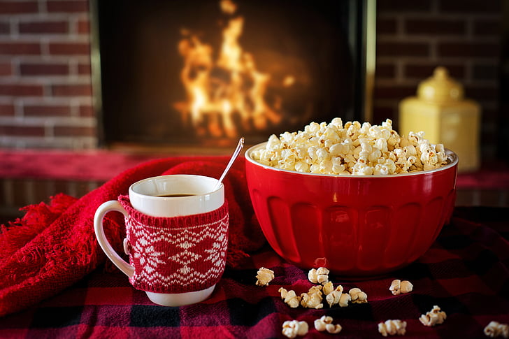 red bowl of popcorn beside coffee mug