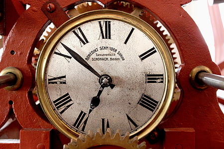 round gold-colored analog clock on red steel frame