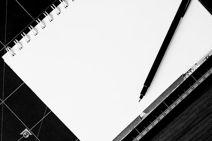 white notebook and black ballpoint pen
