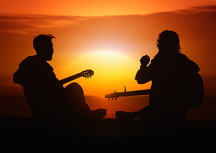 silhouette of men playing guitar during sunset
