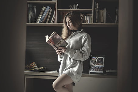 woman in grey loose sweater reading book
