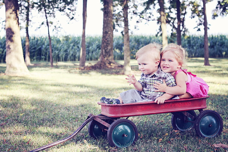 boy and girl riding on pull wagon photograph
