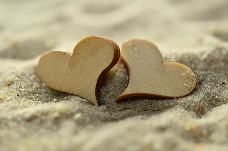 two heart shape wooden decoration on sand